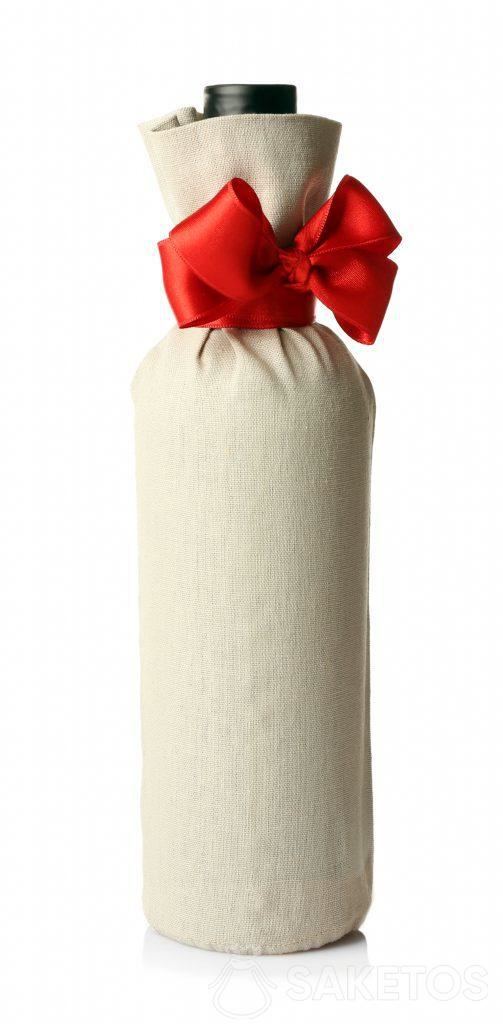 A bottle of alcohol packaged as a gift in a linen bag with a red bow