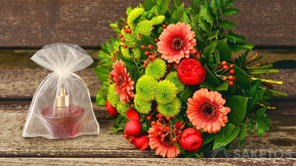 A gift set for a woman - a bouquet of flowers and perfume in an organza bag