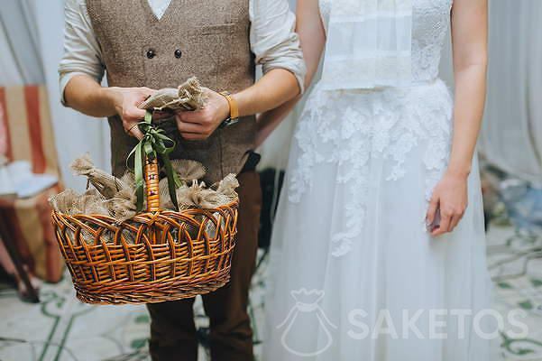 Bride and groom with jute bags with gifts for wedding guests.