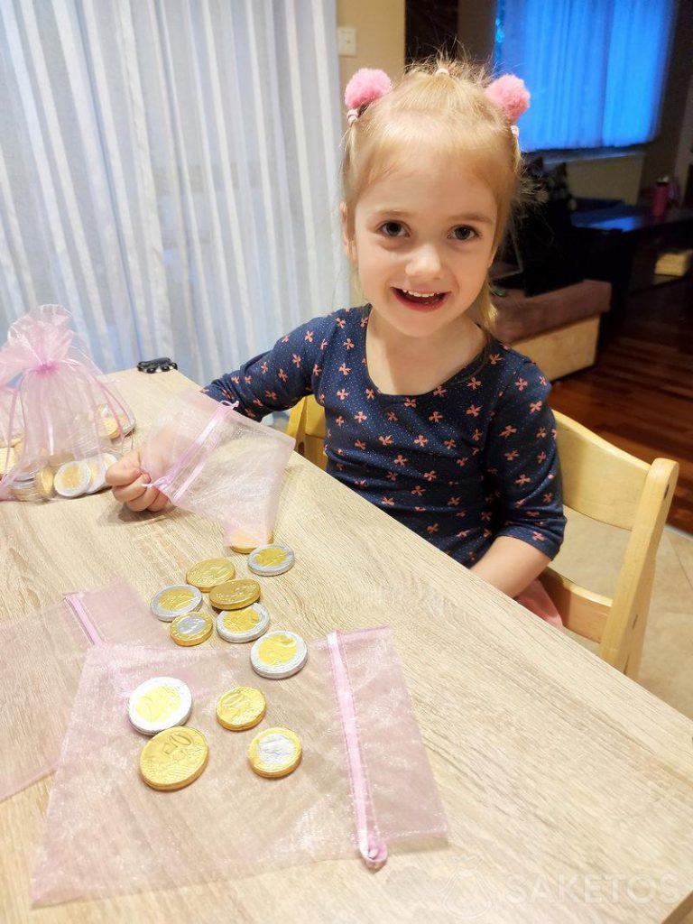 A girl fills organza bags with chocolate coins