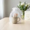 White organza pouch 15x20 cm with a ceramic mug placed inside.