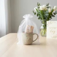 White organza pouch 15x20 cm with a ceramic mug placed inside.