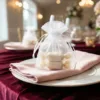 Wedding table decoration using white organza pouches.