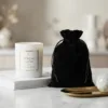 Minimalist white candle placed next to a luxury black velvet pouch.
