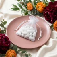 White organza gift bags with sugared almonds for wedding guests.