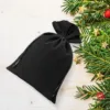 Black velvet pouches for Christmas gifts decorated with a green pine branch.
