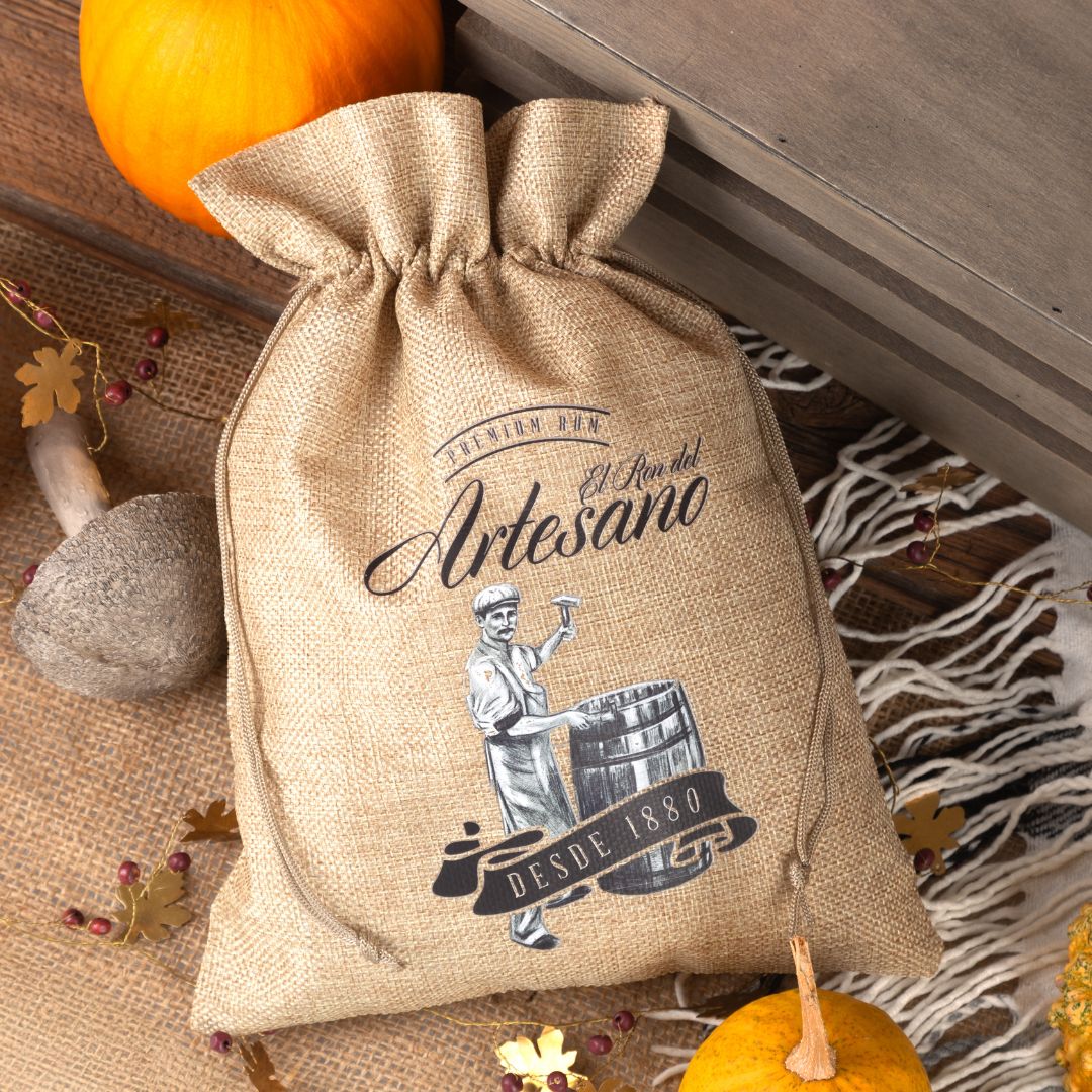 Jute pouch with black "Artesano" print, in front of autumn decoration.