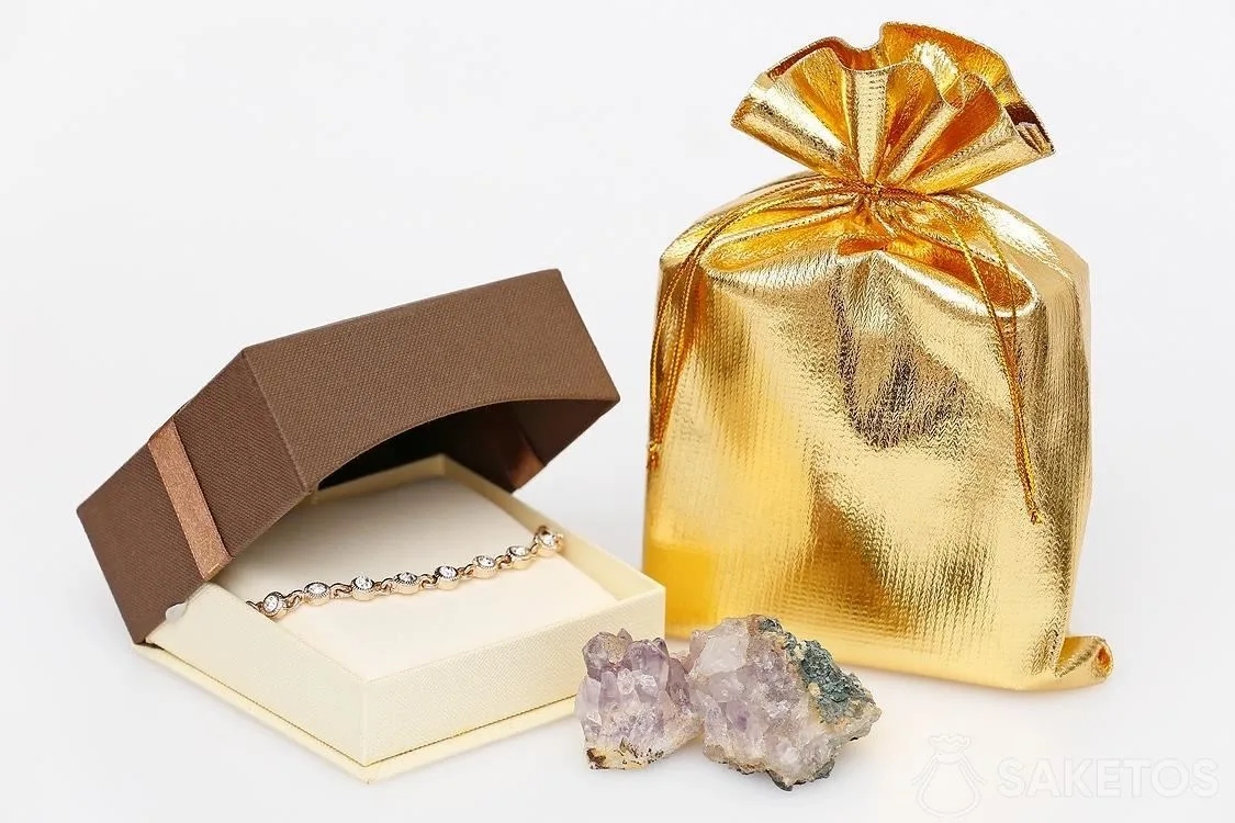 Silver satin bag as an elegant packaging for a cardboard jewelry box with earrings.