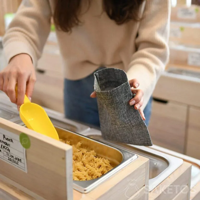 Woman shops by putting bulk products in durable shopping bags - reusable jute packaging