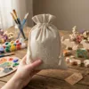 Linen bags held in hand with art supplies and creative materials in the background