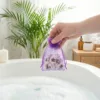 Organza bags held in hand above a bathtub as a bathroom decoration