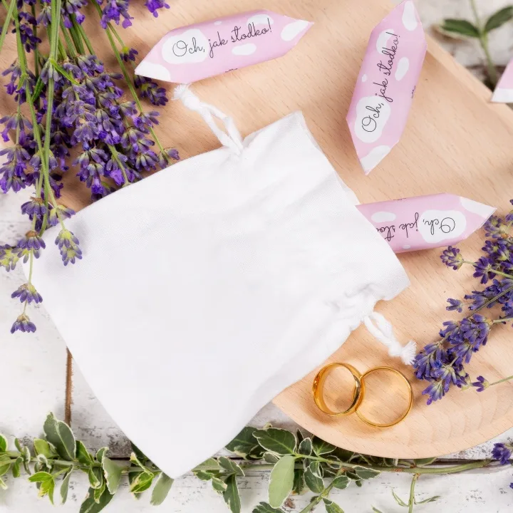 Homepage 10 Elegant white satin drawstring pouch next to golden wedding bands and lavender.
